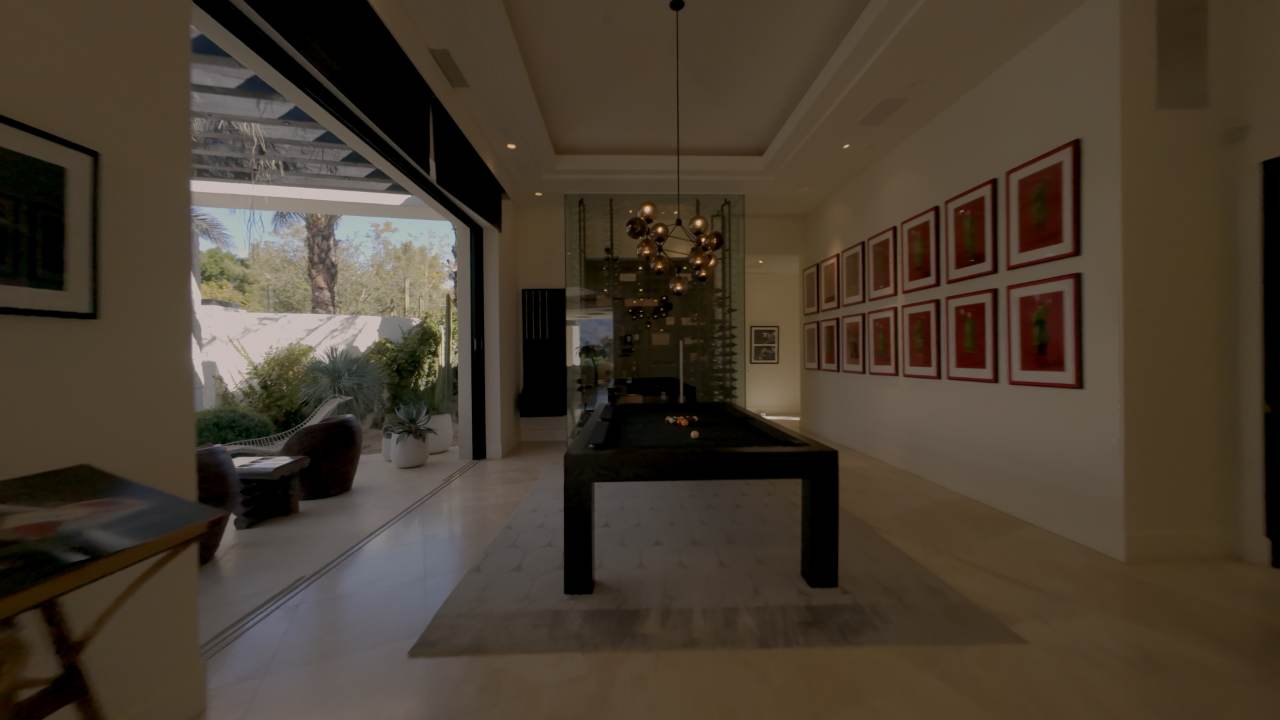Gallery hall hung with framed art, opening into the game room